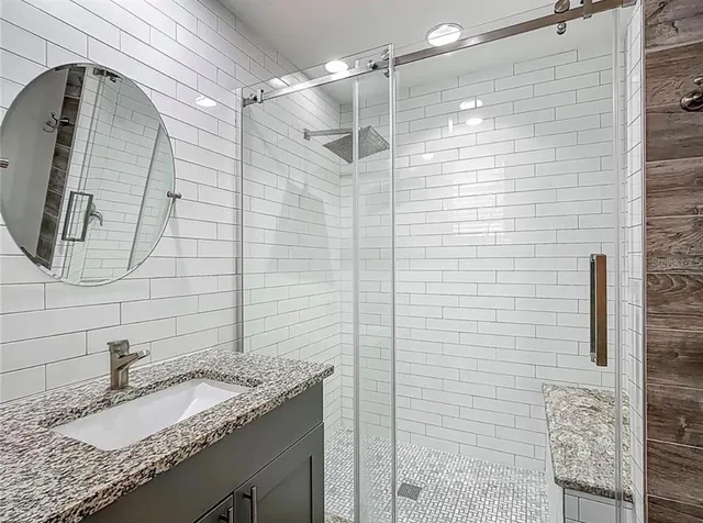 a bathroom with a granite countertop shower sink and mirror
