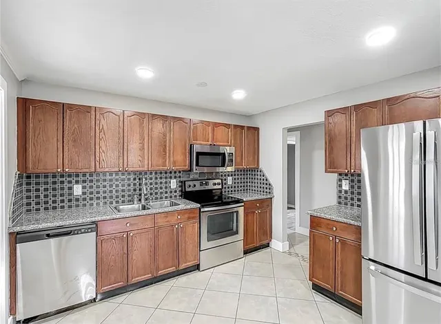 a kitchen with stainless steel appliances granite countertop a stove a sink and a refrigerator