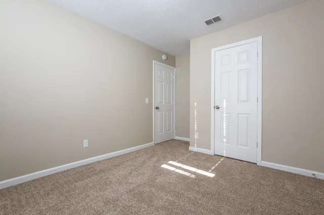 a view of an empty room with windows and chandelier fan