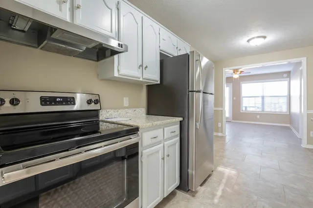 a kitchen with stainless steel appliances a refrigerator a stove and white cabinets