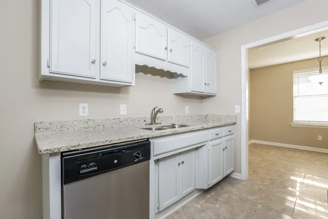 a kitchen with stainless steel appliances granite countertop a sink and dishwasher with white cabinets