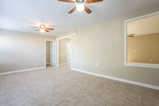 an empty room with windows and fan