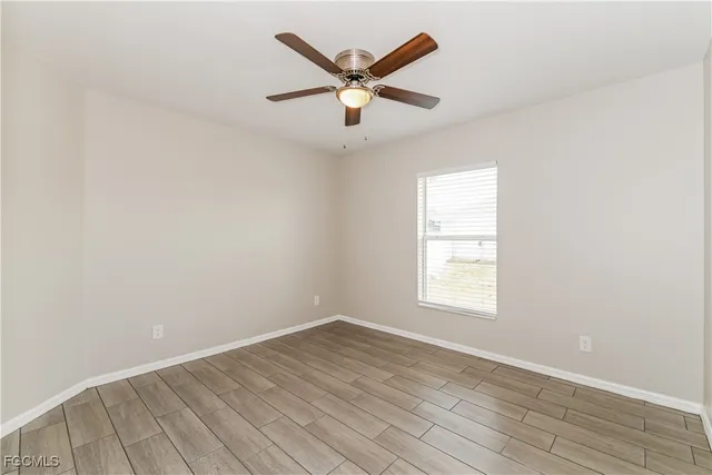 an empty room with wooden floor and ceiling fan