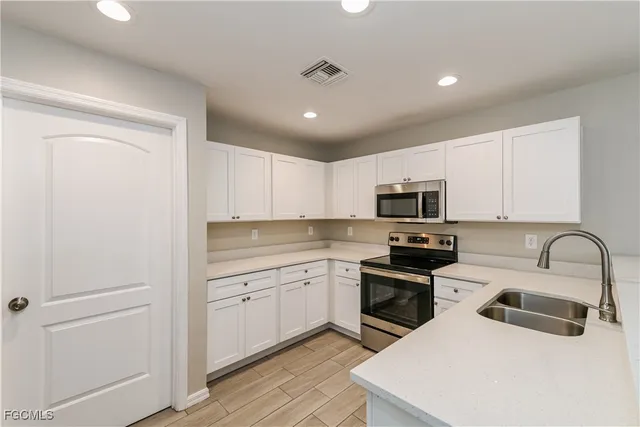 a kitchen with a sink white cabinets and stainless steel appliances