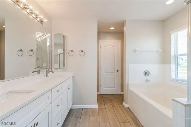 a bathroom with a tub a sink shower and a mirror