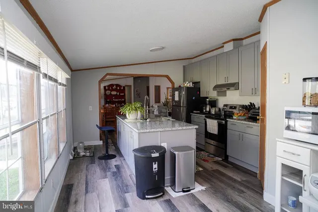 a kitchen with kitchen island a counter top space a sink stainless steel appliances and cabinets