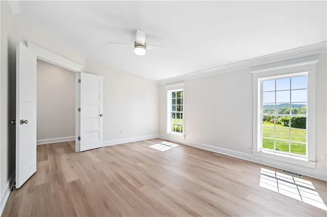 a view of an empty room with wooden floor and a window
