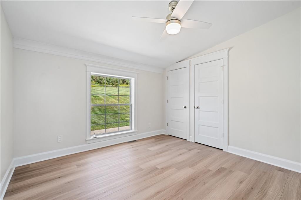 2118 Spooky Hollow Road Lower Burrell, PA 15068 - Photo 23 of 44 an empty room with wooden floor fan and windows
