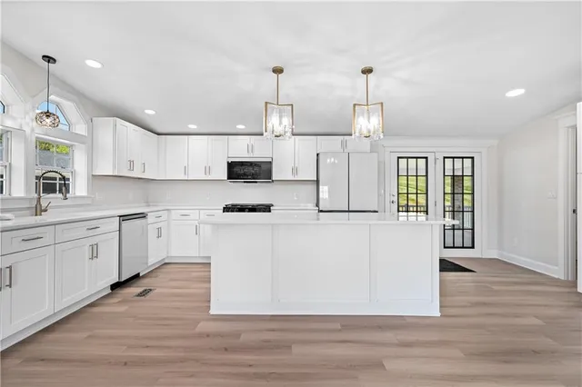 a large kitchen with granite countertop a stove top oven a sink a counter space and cabinets