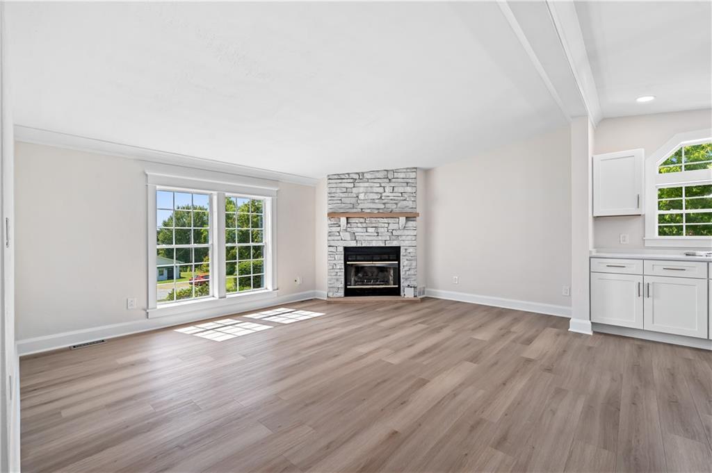 2118 Spooky Hollow Road Lower Burrell, PA 15068 - Photo 9 of 44 an empty room with wooden floor fireplace and windows