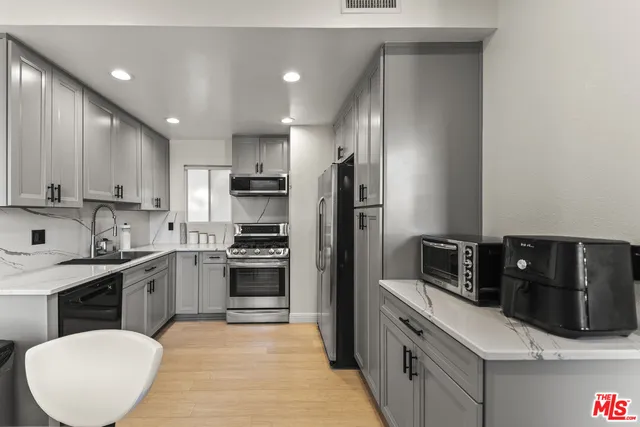 a kitchen with stainless steel appliances granite countertop a refrigerator a stove a sink a microwave and wooden cabinets