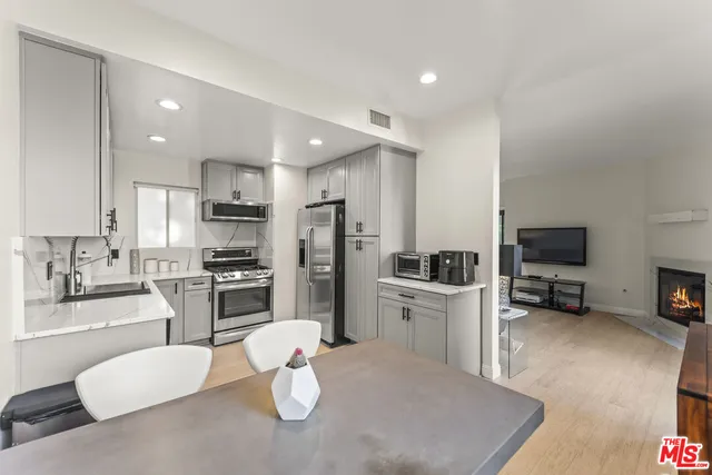 a kitchen with stainless steel appliances kitchen island granite countertop a sink a stove a refrigerator cabinets and a dining table