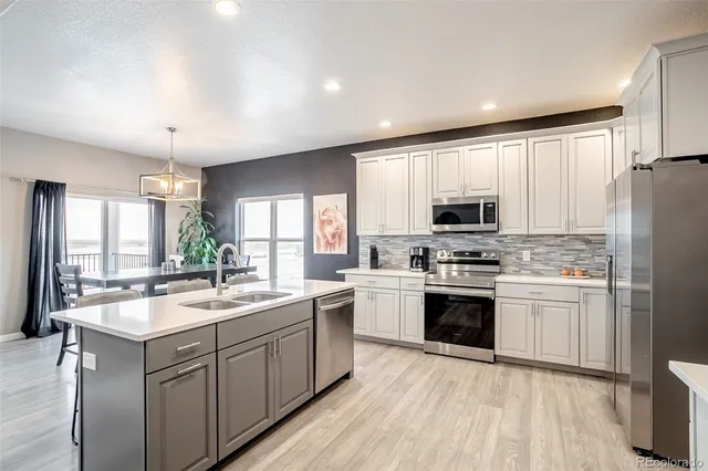 a open kitchen with stainless steel appliances kitchen island granite countertop a table chairs and a wooden floors