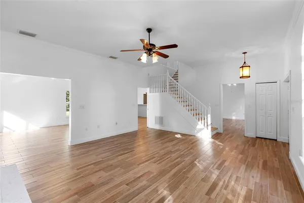 a view of empty room with wooden floor and fan