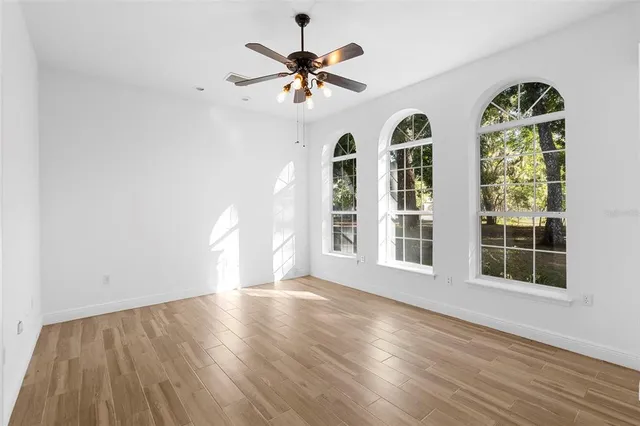 a view of a room with wooden floor and a ceiling fan