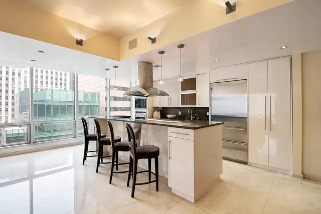 a kitchen with stainless steel appliances a white table chairs and a refrigerator