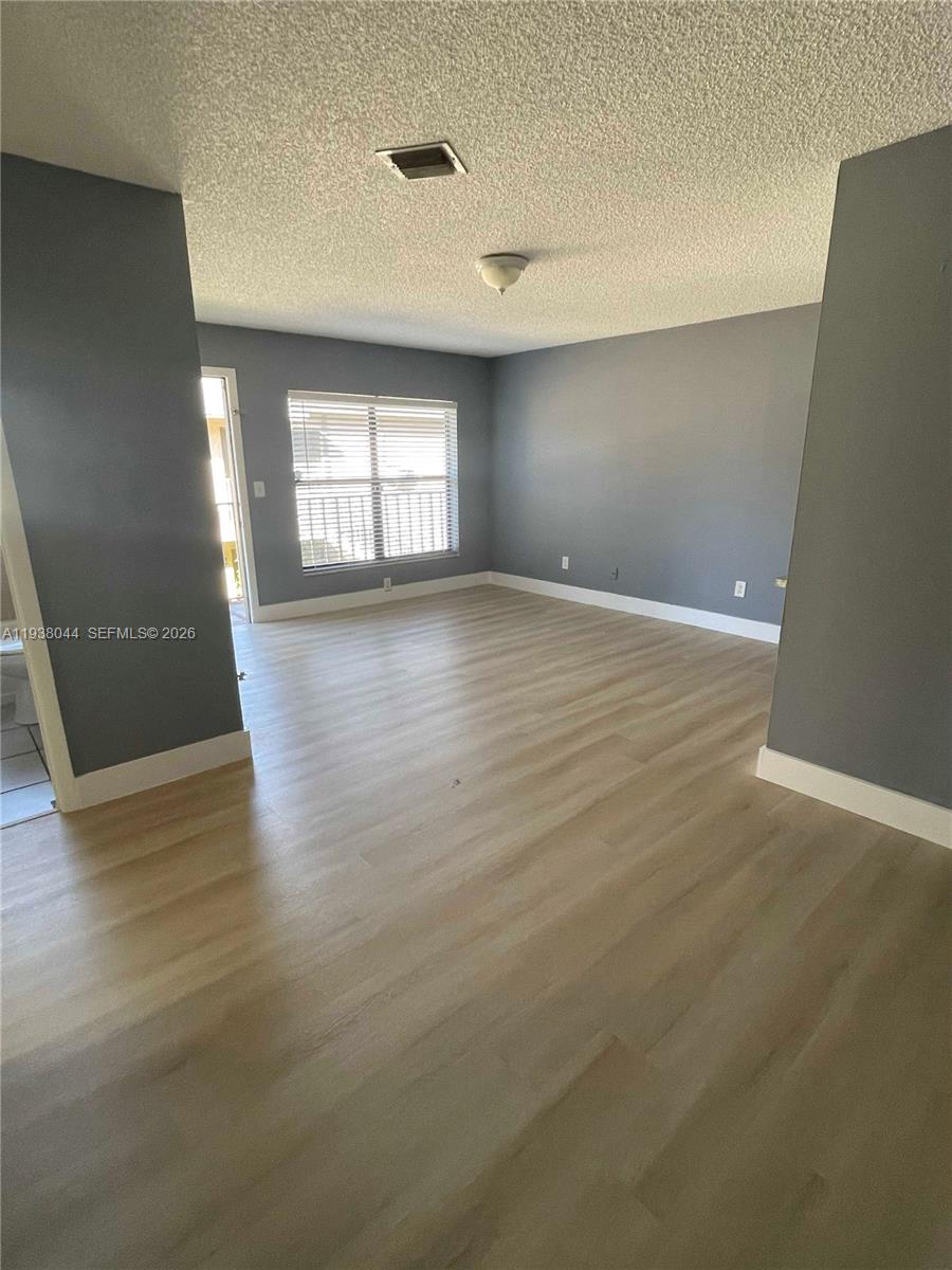 15330 Southwest 72nd Street, Unit 721 Miami, FL 33193 - Photo 7 of 15 an empty room with wooden floor and windows