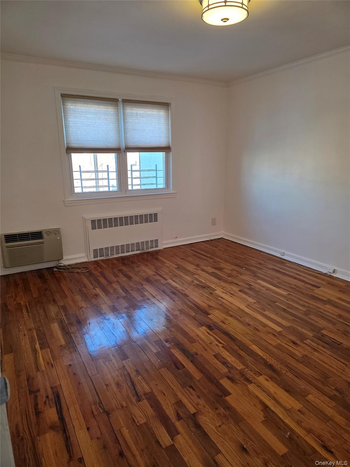 150-25 77th Road Queens, NY 11367 - Photo 4 of 12 an empty room with wooden floor and windows