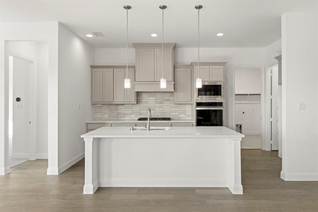 3306 Agnew Street Celina, TX 75009 - Photo 7 of 27 a large white kitchen with kitchen island a sink stainless steel appliances and cabinets