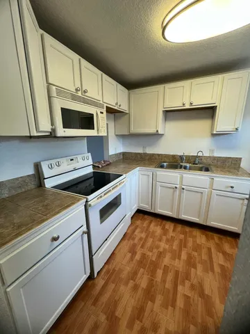 a kitchen with granite countertop white cabinets and a stove