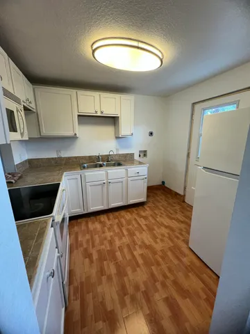 an empty room with wooden floor chandelier and windows