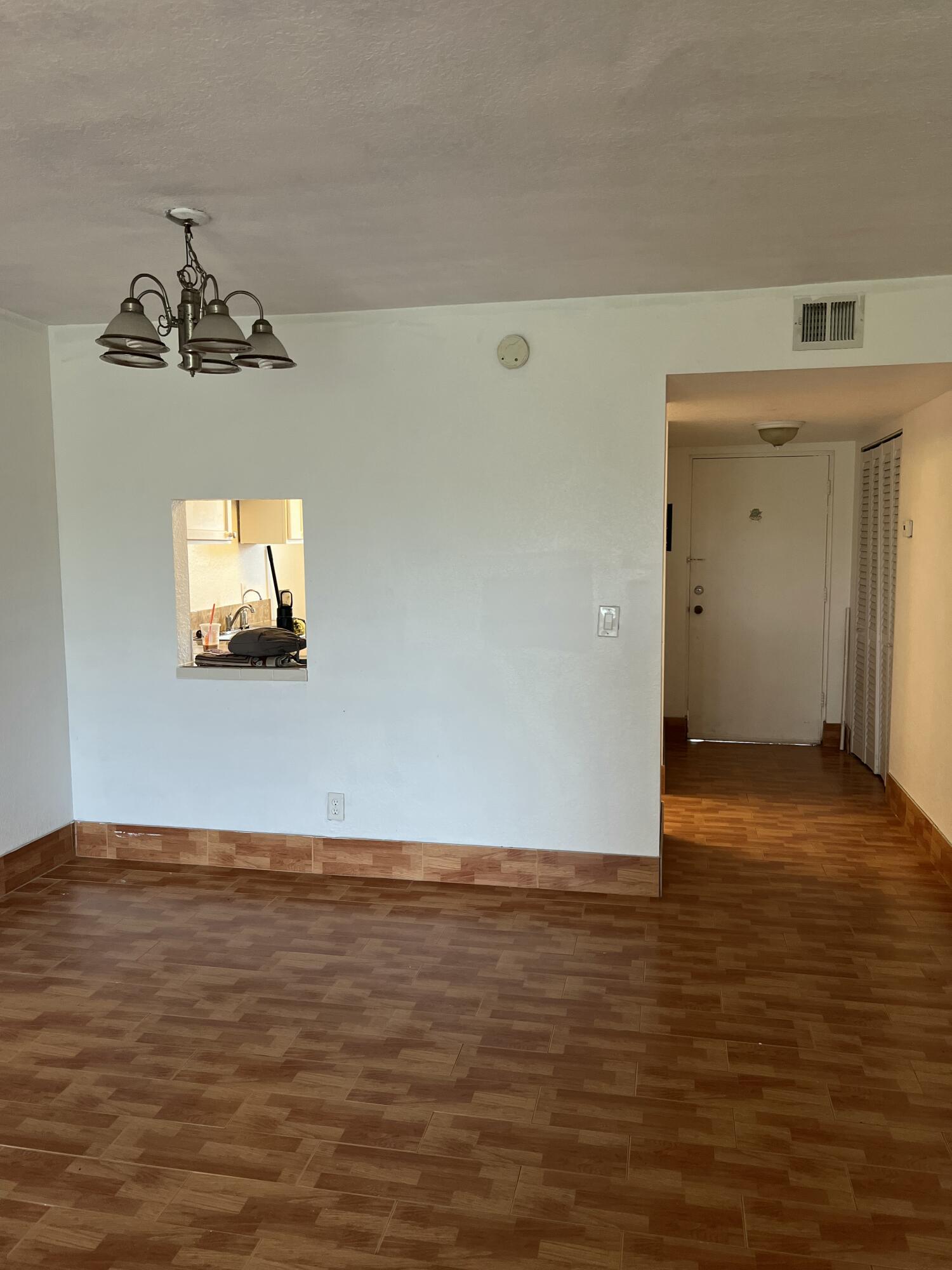 5500 Northwest 2nd Avenue, Unit 121 Boca Raton, FL 33487 - Photo 6 of 28 an empty room with wooden floor chandelier and windows