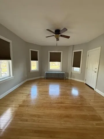 a view of empty room with wooden floor and fan