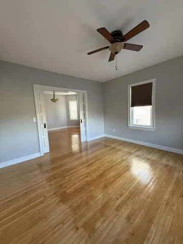a view of empty room with wooden floor and fan