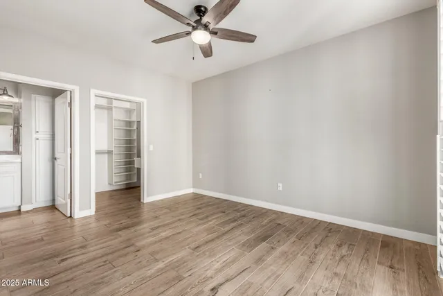an empty room with wooden floor closet and windows