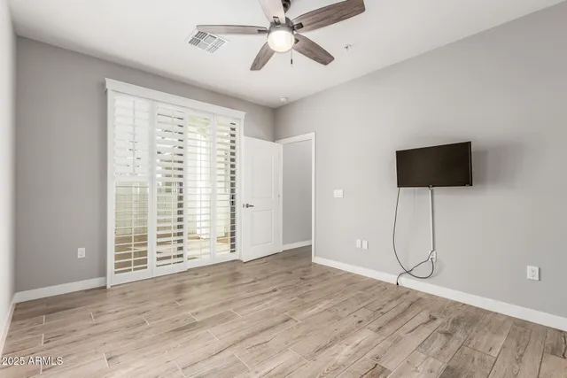 a view of an empty room with a window and wooden floor