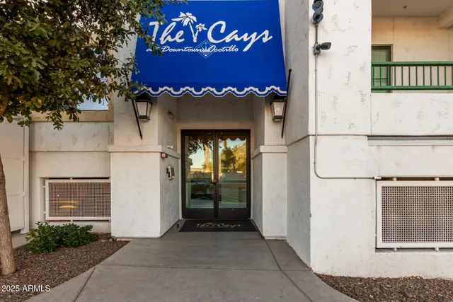 a view of a red sign board with buildings in the background