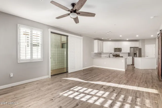 a view of a kitchen with kitchen island stainless steel appliances wooden floor and a window