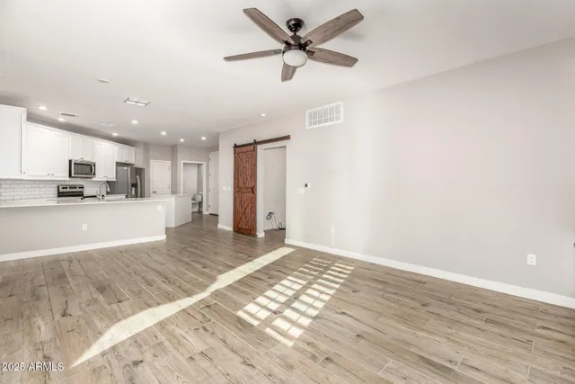 a view of kitchen and empty room with wooden floor