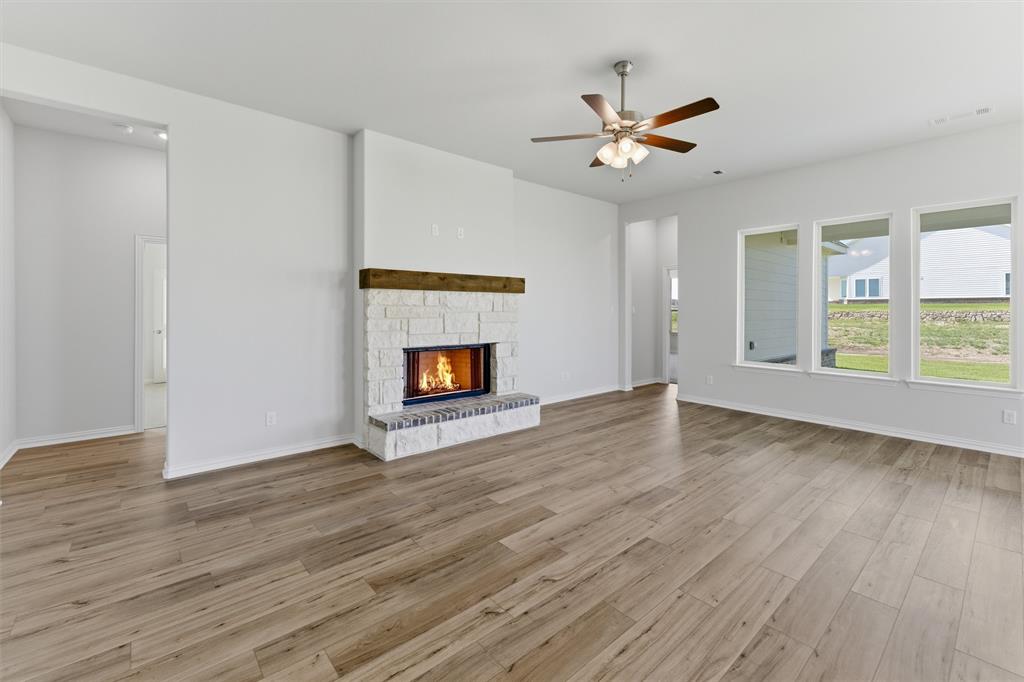 104 Snowy Owl Trail Rhome, TX 76078 - Photo 12 of 27 Spacious living area featuring light wood-finish flooring and a stone fireplace with a substantial wood mantel