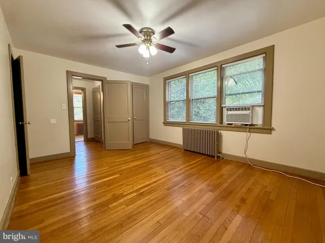 a view of an empty room with a window and wooden floor