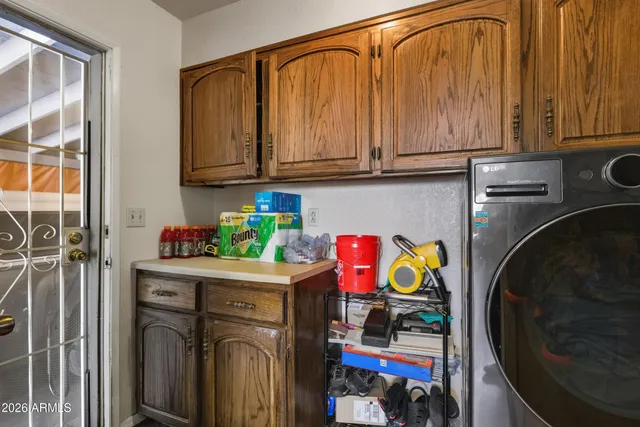 a utility room with fridge and wooden floor