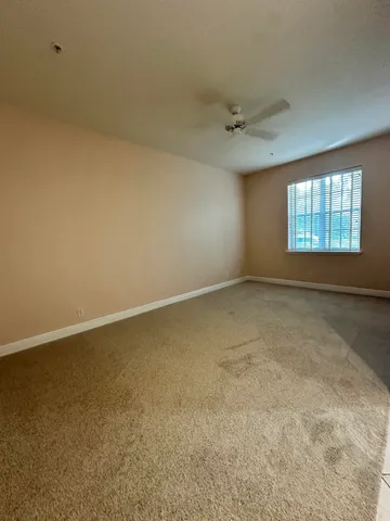 an empty room with windows and ceiling fan