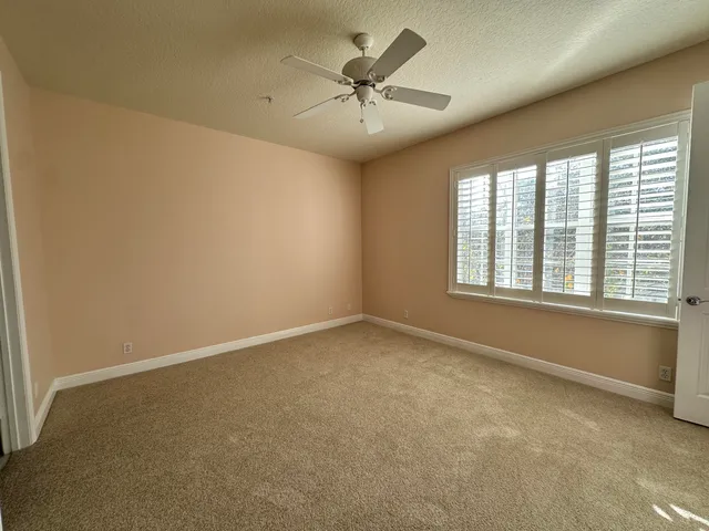 an empty room with a ceiling fan and windows