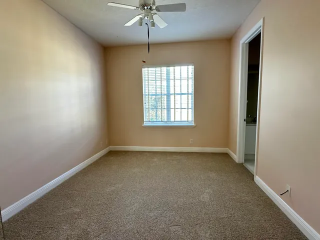 an empty room with a window and a chandelier fan