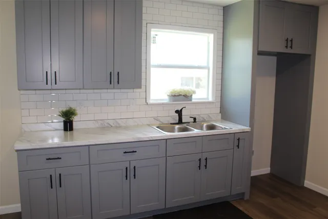 a kitchen with white cabinets and sink
