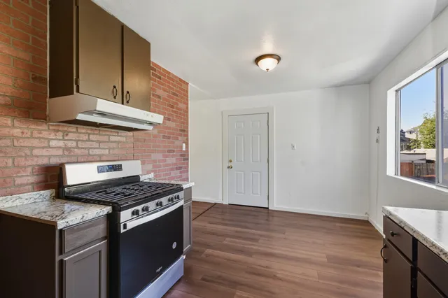 a kitchen with granite countertop a stove and a wooden floor