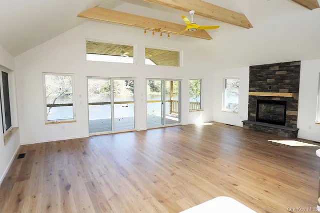 an empty room with wooden floor fireplace and windows