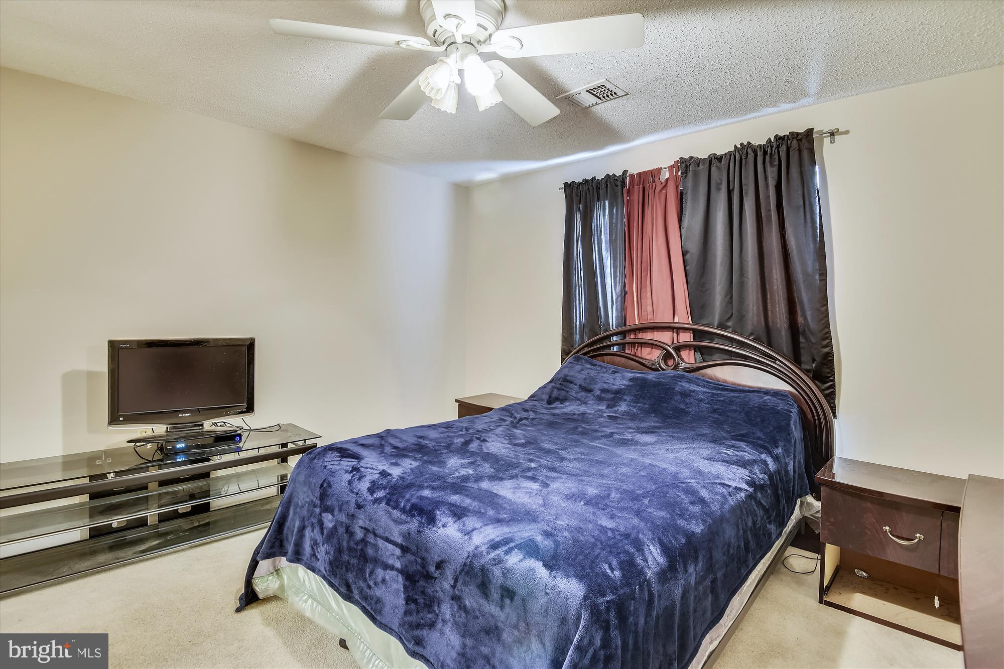 20979 Timber Ridge Terrace, Unit 204 Ashburn, VA 20147 - Photo 13 of 29 a bedroom with a bed and a flat tv screen on a dresser