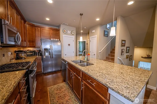 a kitchen with stainless steel appliances granite countertop sink stove refrigerator and cabinets