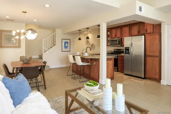 a living room with stainless steel appliances furniture and a kitchen view