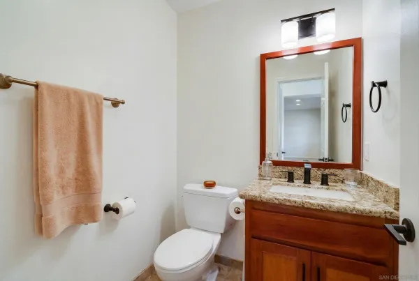 a bathroom with a granite countertop sink toilet and mirror