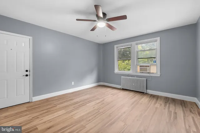 an empty room with wooden floor and ceiling fan