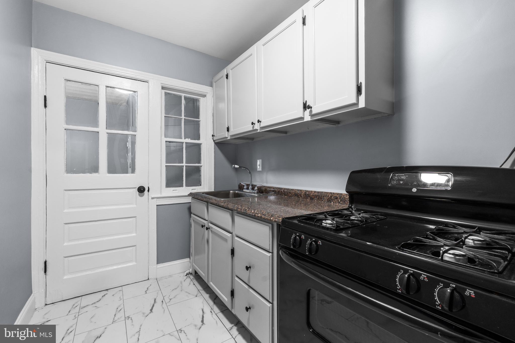 1721 29th Street Southeast, Unit 1 Washington, DC 20020 - Photo 8 of 24 a kitchen with granite countertop a stove and a microwave