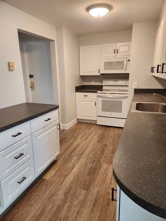 a kitchen with stainless steel appliances a stove a sink and white cabinets with wooden floor