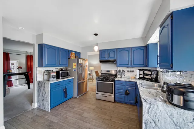 a kitchen with stainless steel appliances granite countertop a stove top oven a sink dishwasher and a refrigerator with wooden cabinets